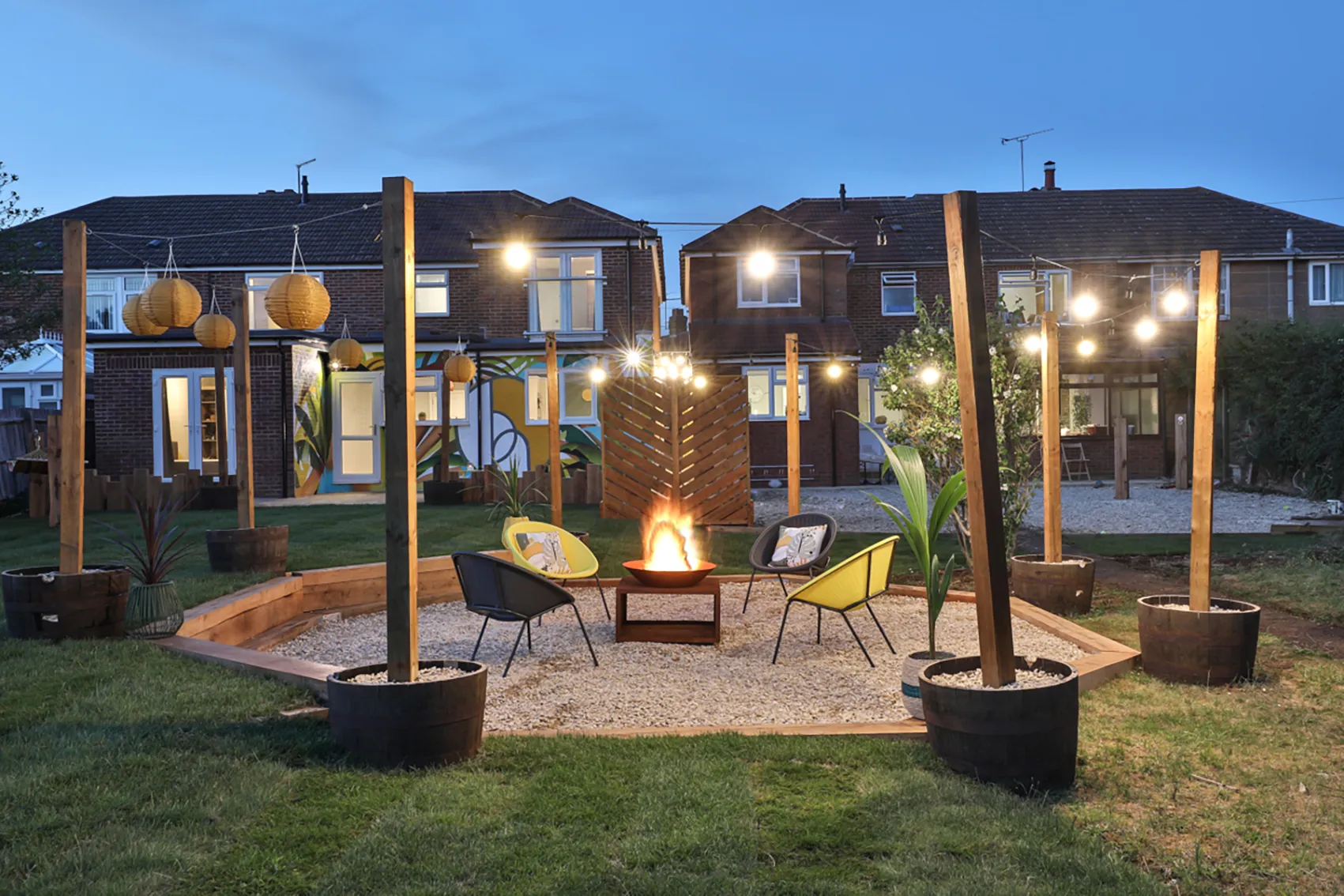 Shared garden with seating around a fire pit and festoon lights